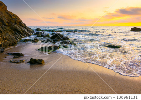 sunrise on the beach. beautiful summer landscape for vacation at the sea. rocks on the sand. calm waves on the water. sun behind clouds on the sky. wide panoramic view of bamboo beach in sozopol sunrise on the beach. beautiful summer landscape for vacation at the sea. rocks on the sand. calm waves on the water. sun behind clouds on the sky. wide panoramic view of bamboo beach in sozopol 130961131