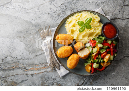 Hot chicken bechamel croquettes with mashed potatoes, vegetable salad and ketchup close-up in a plate. Horizontal top view Hot chicken bechamel croquettes with mashed potatoes, vegetable salad and ketchup close-up in a plate. Horizontal top view 130961190