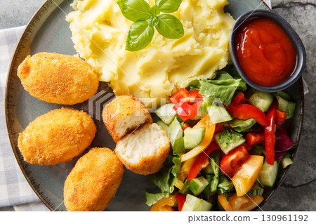 Breaded and fried chicken Croquettes served with mashed potatoes, fresh salad and tomato sauce close-up in a plate. Horizontal top view Breaded and fried chicken Croquettes served with mashed potatoes, fresh salad and tomato sauce close-up in a plate. Horizontal top view 130961192