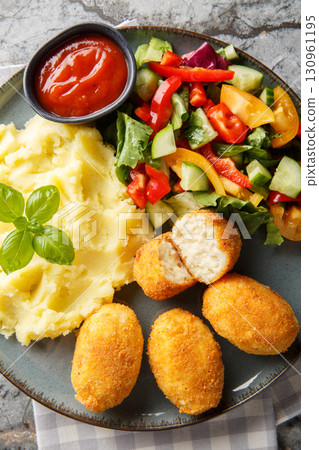 Delicious crispy fried breaded chicken croquettes served with potatoes, fresh salad and tomato sauce close-up in a plate on the table. Vertical top view Delicious crispy fried breaded chicken croquettes served with potatoes, fresh salad and tomato sauce close-up in a plate on the table. Vertical top view 130961195