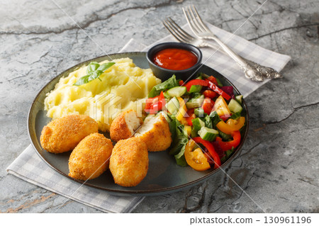 Hot chicken bechamel croquettes with mashed potatoes, vegetable salad and ketchup close-up in a plate. Horizontal 130961196