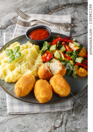 Close-up of Spanish chicken croquettes with mashed potatoes, vegetable salad, and ketchup in a plate. Vertical 130961199