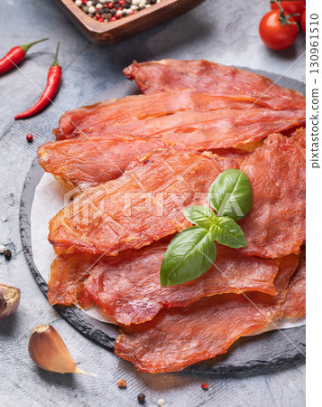 Dried chicken meat on stone tray with fresh basil leaf and various spices on table 130961510