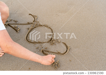 Hand writes numbers in the sand. Two and zero Hand writes numbers in the sand. Two and zero 130961590