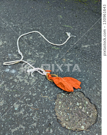 A popped children's balloon on white string abandoned on a path 130961643