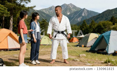 A judoka talking to a young woman at a campsite 130961815