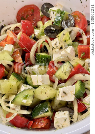 A vibrant Mediterranean salad featuring tomatoes, cucumbers, olives, and feta cheese, perfect for any meal. Close-up. A vibrant Mediterranean salad featuring tomatoes, cucumbers, olives, and feta cheese, perfect for any meal. Close-up. 130962251