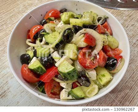 A vibrant Mediterranean salad featuring tomatoes, cucumbers, olives, and feta cheese, perfect for any meal. Close-up. A vibrant Mediterranean salad featuring tomatoes, cucumbers, olives, and feta cheese, perfect for any meal. Close-up. 130962267