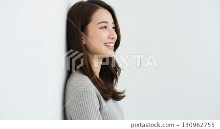 Natural looking young Asian woman smiling against a light background 130962755