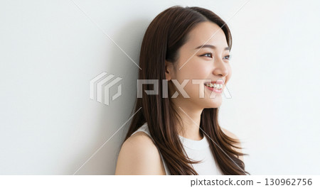 Natural looking young Asian woman smiling against a light background 130962756
