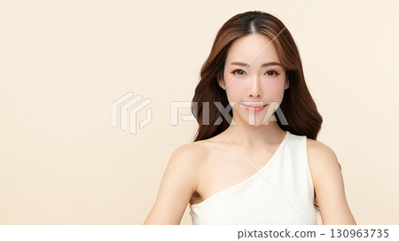 A beautiful young Asian woman with clean, fresh skin against a beige background. Skincare, facial treatment, cosmetology, beauty, and spa. An elegant portrait of an Asian woman. 130963735
