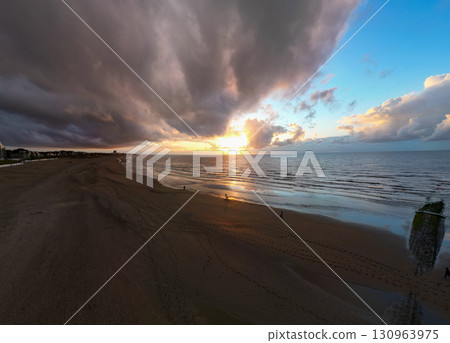 A stunningly beautiful beach sunset showcases dramatic clouds above tranquil waters and the horizon A stunningly beautiful beach sunset showcases dramatic clouds above tranquil waters and the horizon 130963975