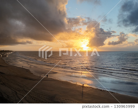 Experience the Serene Sunset Over the Tranquil Beach Accompanied by Gentle Waves and Clouds 130963999