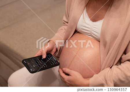 Pregnant woman looking at calendar in her phone. Baby birth date concept. 130964357