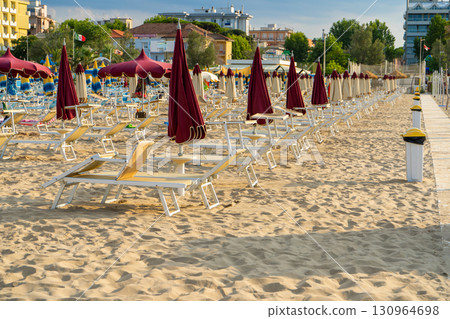 Sun loungers on a sandy beach Umbrella and empty chairs on seaside resort. Italy. Sun loungers on a sandy beach Umbrella and empty chairs on seaside resort. Italy. 130964698