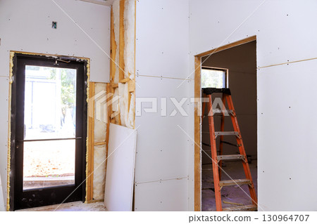 Drywall installation process in residential building during work daytime near window Drywall installation process in residential building during work daytime near window 130964707