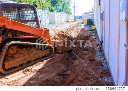 Excavation work in progress near building with small construction vehicle on works day 130964717