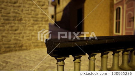 Evening light casts warm tones on a cobblestone street in a quiet town. The textured stone walls frame the pathway, creating a serene atmosphere for evening strolls. 130965286