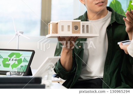 ESG principles in action. Professionals discussing sustainable architecture with model buildings. 130965294