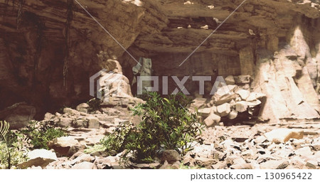 Inside a secluded cave, natural light illuminates rocky formations and patches of greenery. The rugged terrain showcases unique geological features and peaceful surroundings. 130965422