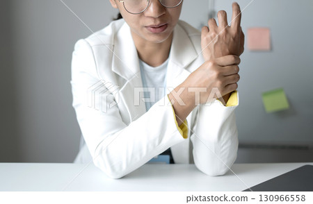 Woman hand with wrist pain numbness and pain in the palm of the hand has pain and tingling in the nerve endings This is a side effect of sitting and working for a long time on a laptop at the office Woman hand with wrist pain numbness and pain in the palm of the hand has pain and tingling in the nerve endings This is a side effect of sitting and working for a long time on a laptop at the office 130966558