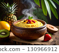 A Nigerien calabash bowl filled with steaming millet porridge placed beside fresh tropical fruits. 130966912