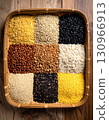 A collection of dried seeds and grains are laid out on a traditional woven tray. 130966913