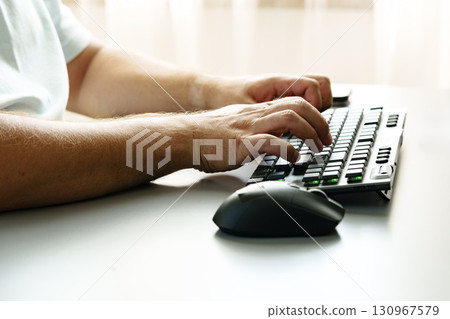 Person typing on a keyboard with a mouse beside on a minimal workspace desk Person typing on a keyboard with a mouse beside on a minimal workspace desk 130967579