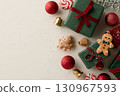 Delightful holiday tableau from top view emerald gift boxes, red, green, and golden baubles, gingerbread man ornament, jingle bells, candies, frosty fir twig, light background with space for greeting 130967593