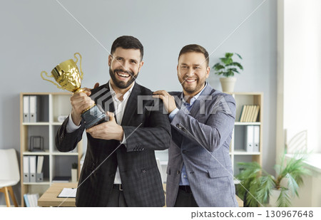Young happy business people holding trophy award for best employee reward Young happy business people holding trophy award for best employee reward 130967648