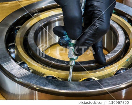 Technician works on industrial bearing assembly in a manufacturing facility during the day 130967800
