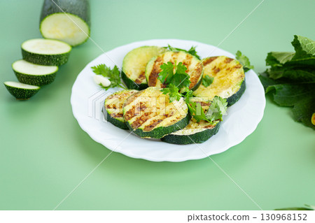 Grilled zucchini slices on a bright green background 130968152