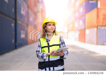 Engineer women wear yellow helmets and reflection shirts working on tablet computers to check inventory details of containers box. Inspector or Safety Supervisor in Container Terminal. Engineer women wear yellow helmets and reflection shirts working on tablet computers to check inventory details of containers box. Inspector or Safety Supervisor in Container Terminal. 130968236