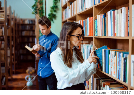 College students looking through different books at library to find necessary information and get ready for classes 130968317