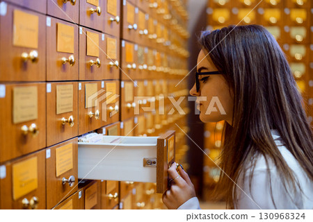 Library or archive reference card catalog. Student girl trying to find necessary book using library paper database Library or archive reference card catalog. Student girl trying to find necessary book using library paper database 130968324