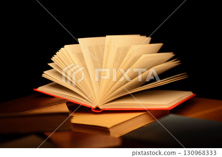 Red open book on the table with many other closed books with beam of light coming straight to the open pages of the book Red open book on the table with many other closed books with beam of light coming straight to the open pages of the book 130968333