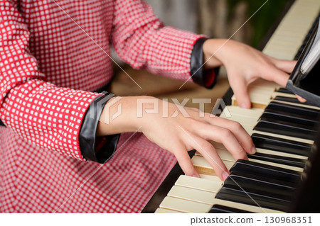 Smart little girl playing the piano at home. Small child learning to play the piano at home, getting ready to the classes in music school 130968351