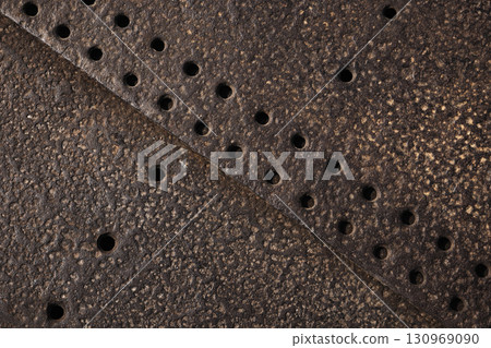 Detailed view of a textured rusty metal surface with punched holes Detailed view of a textured rusty metal surface with punched holes 130969090