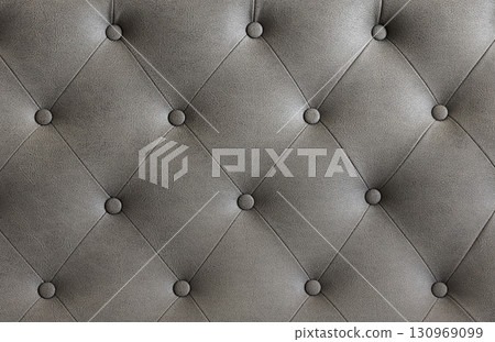 Closeup view of textured gray leather upholstery with elegant tufting 130969099
