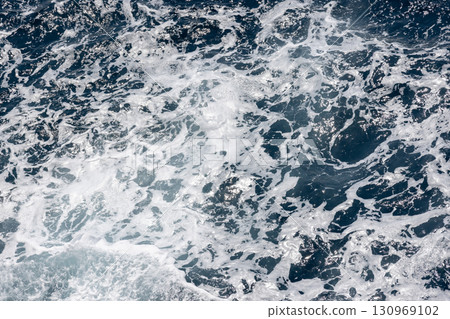 Dynamic ocean waves creating intricate white foam patterns on the surface Dynamic ocean waves creating intricate white foam patterns on the surface 130969102