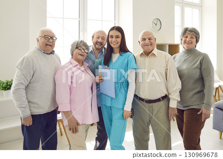 Group of senior people standing with a young nurse and looking cheerful at camera. Group of senior people standing with a young nurse and looking cheerful at camera. 130969678