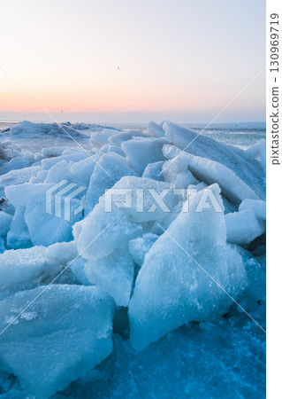 Ice slabs on a frozen coastline at sunset, glowing with evening light and deep blue shadows. Ice slabs on a frozen coastline at sunset, glowing with evening light and deep blue shadows. 130969719