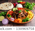 A plate of Mauritanian lamb mechoui surrounded by flatbreads and fresh vegetables on a table. 130969758