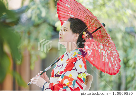 一個穿著和服的年輕女子拿著一把日本雨傘 一個穿著和服的年輕女子拿著一把日本雨傘 130969850