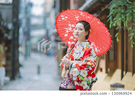 一個穿著和服的年輕女子拿著一把日本雨傘 130969924