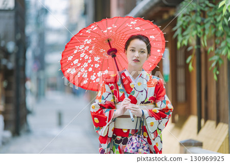 一個穿著和服的年輕女子拿著一把日本雨傘 一個穿著和服的年輕女子拿著一把日本雨傘 130969925