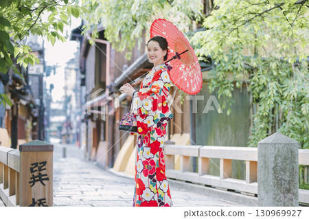 一個穿著和服的年輕女子拿著一把日本雨傘 130969927