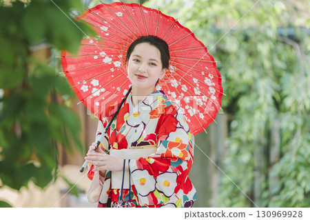 A young woman in a kimono holding a Japanese umbrella A young woman in a kimono holding a Japanese umbrella 130969928