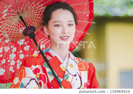 一個穿著和服的年輕女子拿著一把日本雨傘 一個穿著和服的年輕女子拿著一把日本雨傘 130969929