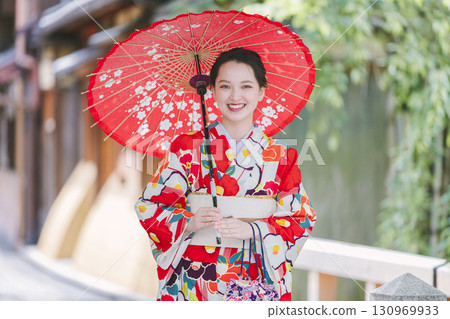 一個穿著和服的年輕女子拿著一把日本雨傘 130969933